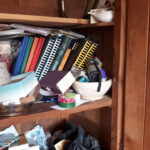 Armoire très encombrée avec de divers objets : plateaux, albums photos, vieux téléphones, souvenirs, cadeaux, etc.
