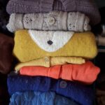 Gros plan sur le pliage vertical des pulls enfants rangés par couleur.